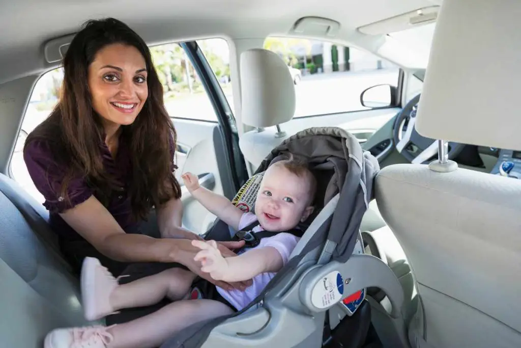 Mãe colocando o bebê na cadeirinha no carro